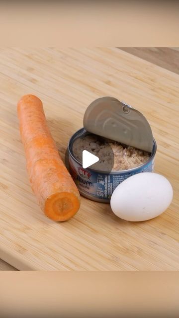 an egg and carrot are on a cutting board next to a can of canned food