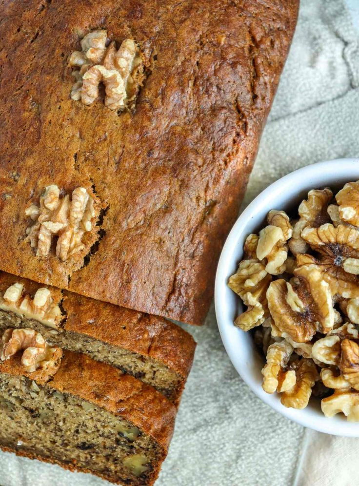 a loaf of banana nut bread next to a bowl of walnuts