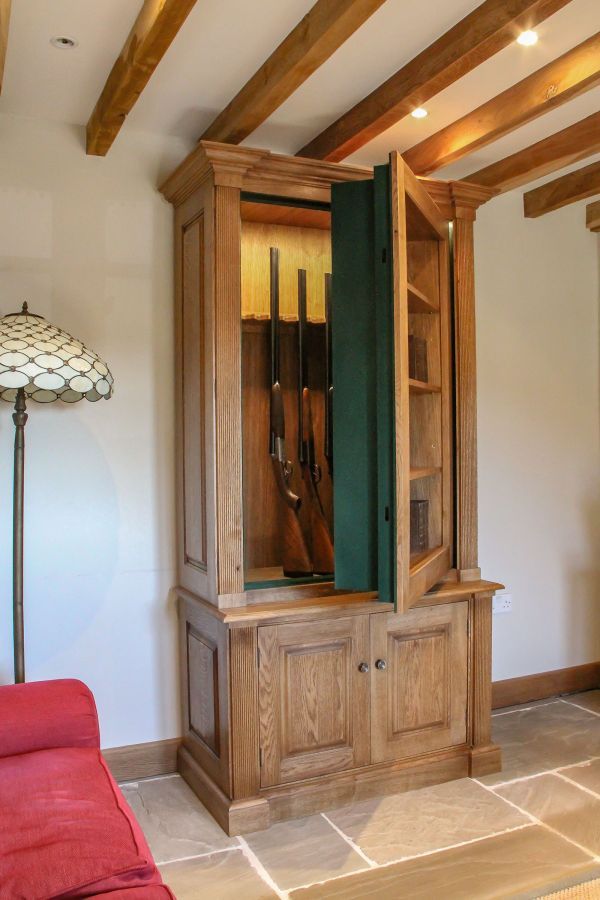 a wooden cabinet sitting in the corner of a living room next to a red couch