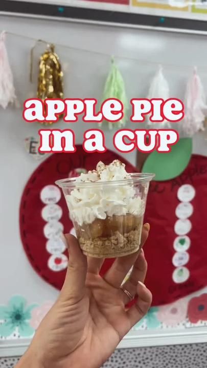 a person holding up a cup with whipped cream in it and the words apple pie in a cup