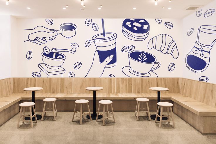 a coffee shop with benches and stools in front of a wall painted with cartoon images