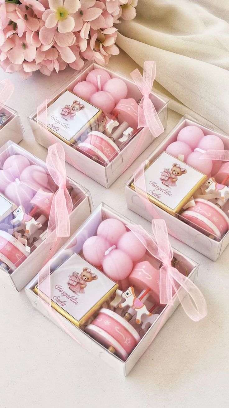 four boxes filled with pink and white treats on top of a table next to flowers