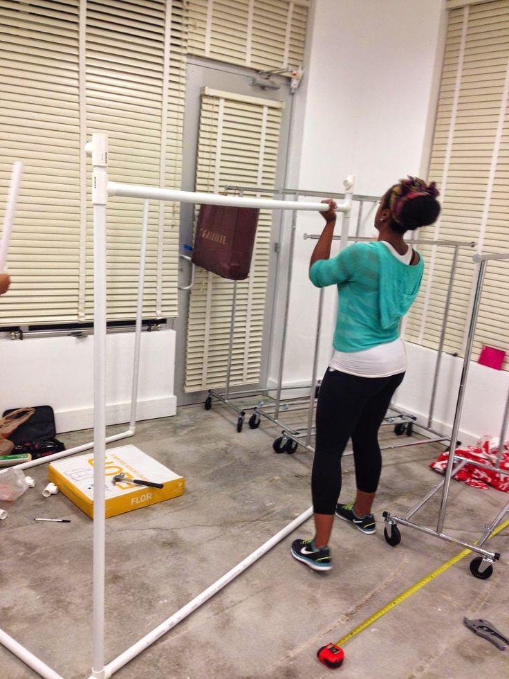 two people in a room with some metal bars on the floor and one person standing up