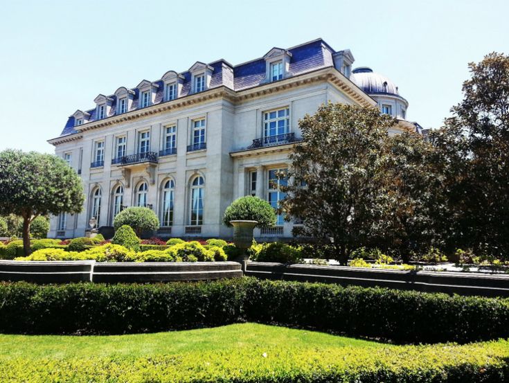 a large white building surrounded by hedges and trees