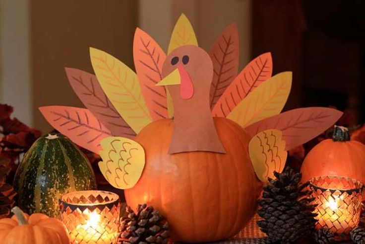 a turkey sitting on top of a table surrounded by pumpkins and pineconis