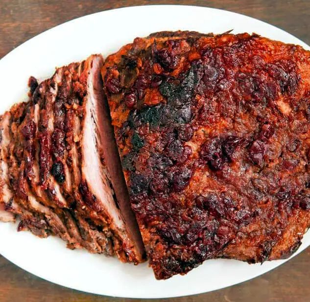 a white plate topped with meat covered in cranberry sauce and sliced into slices