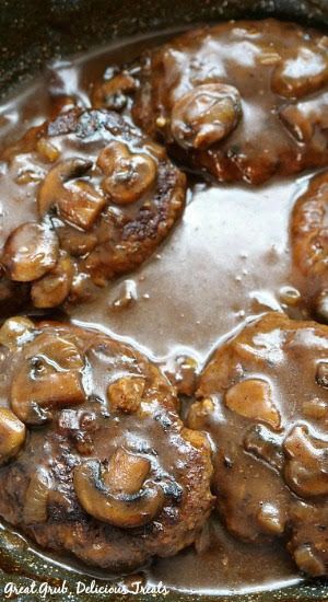 mushrooms are being cooked in a skillet with brown gravy on the side