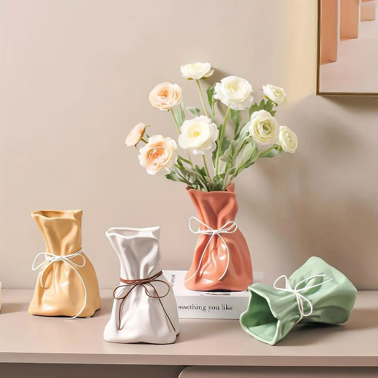 three different colored vases with flowers in them on a table next to each other