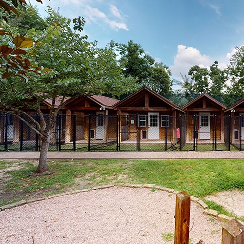 a row of wooden cabins sitting next to each other on top of a lush green field