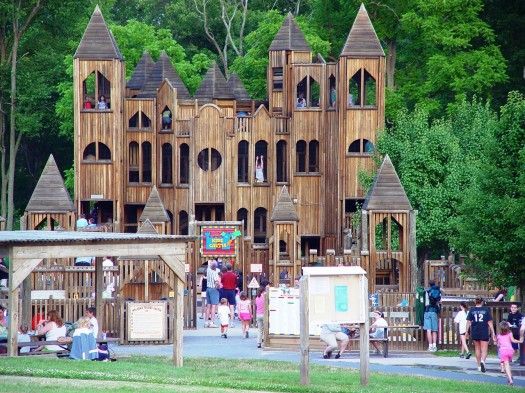 people are walking around in front of a wooden castle