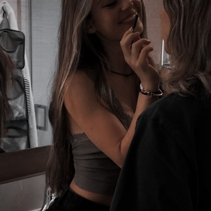 a woman talking on her cell phone in front of a mirror with another person taking a photo