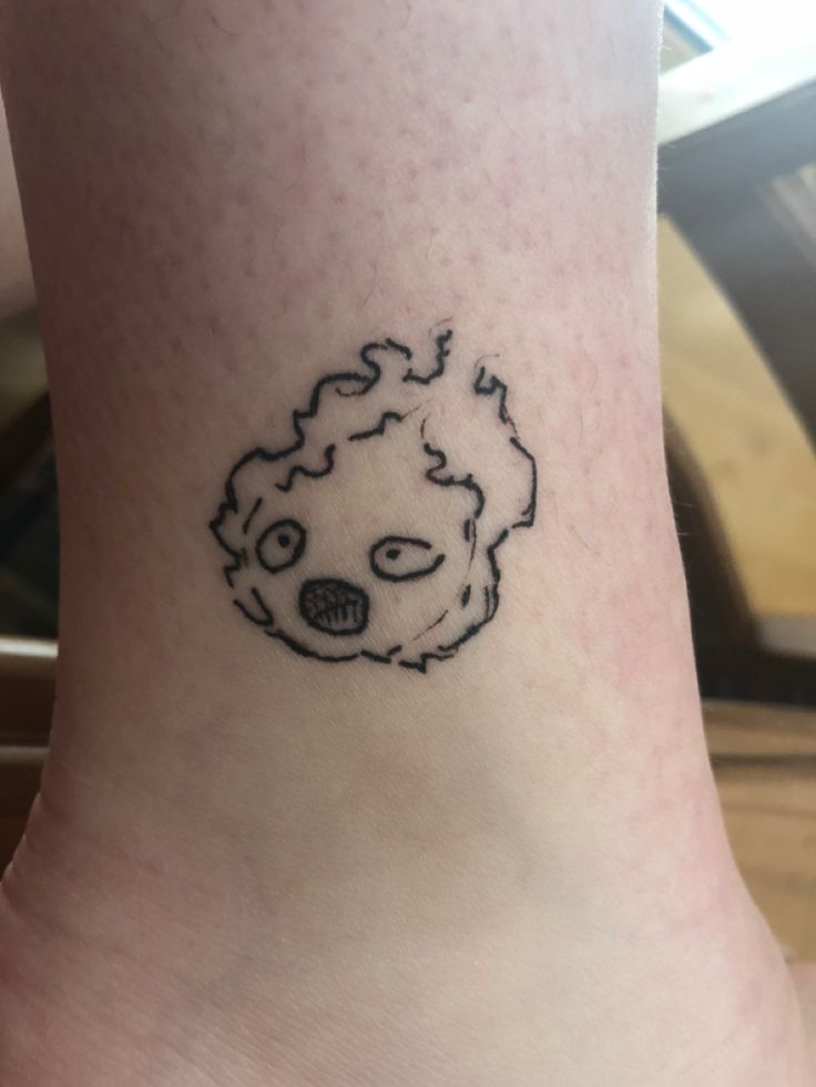 a small tattoo on the ankle of a person's foot with a black and white drawing of a face