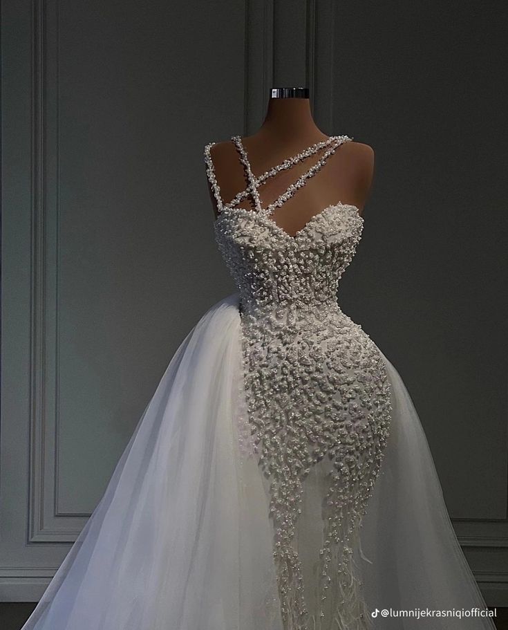 a white wedding dress with flowers on the back and neckline is displayed in front of a mannequin