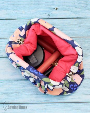 the inside of a purse on a blue wooden table with scissors and other items in it