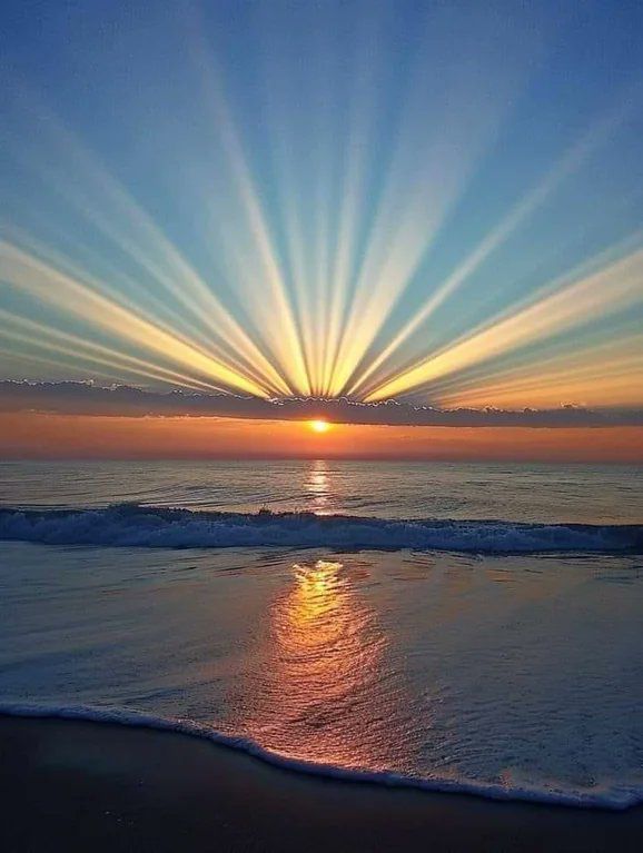 the sun is setting over the ocean with bright rays coming out from it's horizon