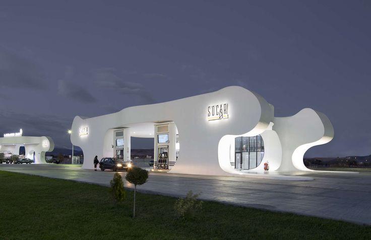 a white building that is lit up at night with people walking around the front entrance