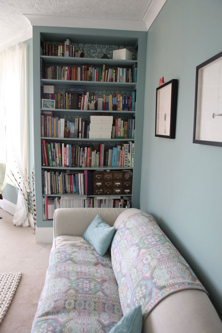 a living room with a couch and bookshelf filled with lots of bookcases