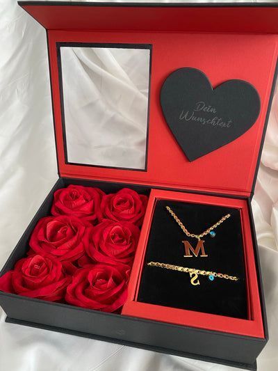 red roses in a black box with a heart necklace and two matching bracelets on it