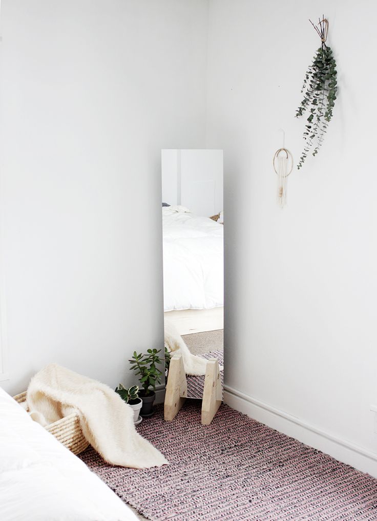 a bedroom with a bed, mirror and plant on the floor in front of it