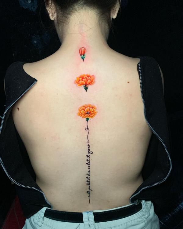 the back of a woman's neck with three flowers on it