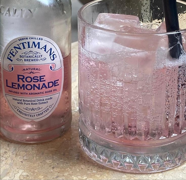 a bottle of rose lemonade next to a glass filled with ice