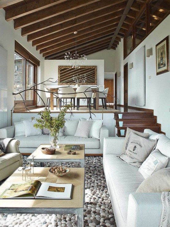 a living room filled with white furniture and lots of wooden beams on top of it