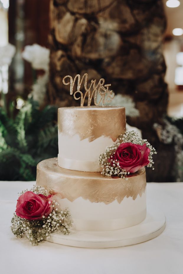 a wedding cake with two red roses on top