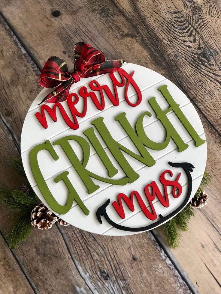 a sign that says merry grinch mays with pine cones and bows on it