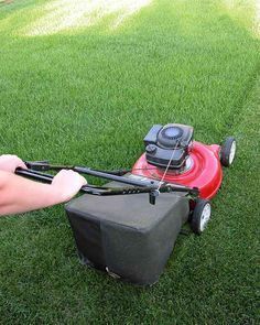 a lawn mower being held over by someone's hand on top of it