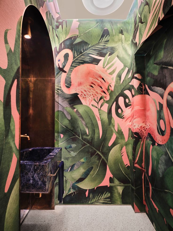 a bathroom with pink flamingos and green leaves on the wall