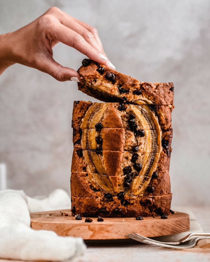 someone cutting into a loaf of bread on top of a wooden board