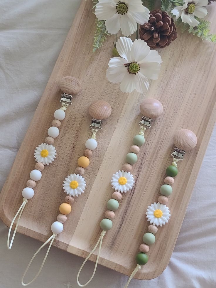 four wooden beads with flowers on them are sitting on a tray next to white daisies