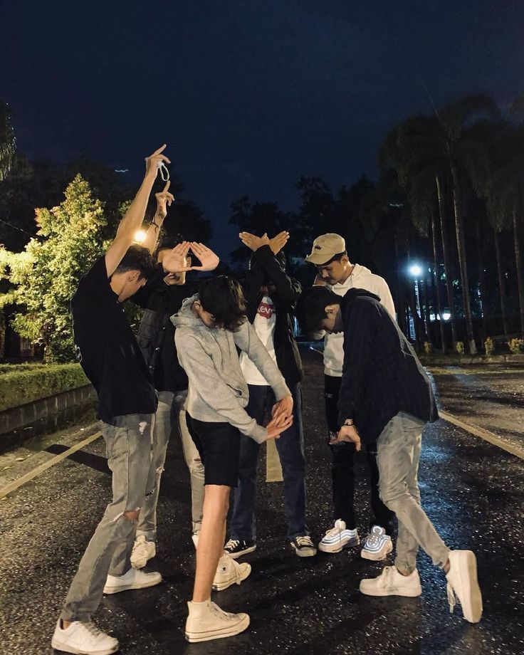 group of people standing in the middle of a street at night with their hands up