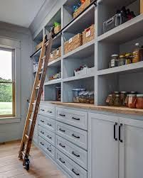 a ladder is leaning up against the wall in a kitchen with white cabinets and drawers