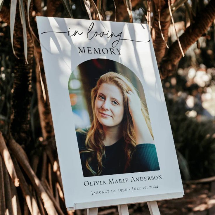 a memorial sign with a photo of an older woman in loving memory is hanging from a tree