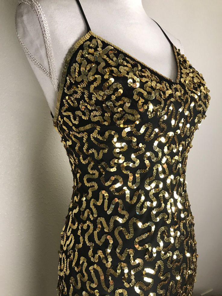 Well nowhello you gorgeous dress! This vintage beauty is from Betsey Johnson's New York Collection and is covered with trailing designs done in gold sequins on a black net background. It is sleeveless with black spaghetti straps which crisscross the back. It is fully lined and has a side zipper. It is in very good preowned condition. It is a size 6 but keep in mind that Betsey's clothes tend to run small so check measurements below. Measurements are taken with garment laying flat.  15 inches und Fitted V-neck Sequin Dress For Festive Occasions, Gold Sleeveless Mini Dress With Contrast Sequin, Gold Mini Dress With Contrast Sequin For Evening, Gold Sleeveless Holiday Evening Dress, Gold Contrast Sequin Mini Dress For Evening, Gold Sleeveless Sequined Evening Dress, Gold Sleeveless Evening Dress With Sequins, Gold Embellished Sleeveless Sequin Dress, Gold Summer Dress With Contrast Sequin