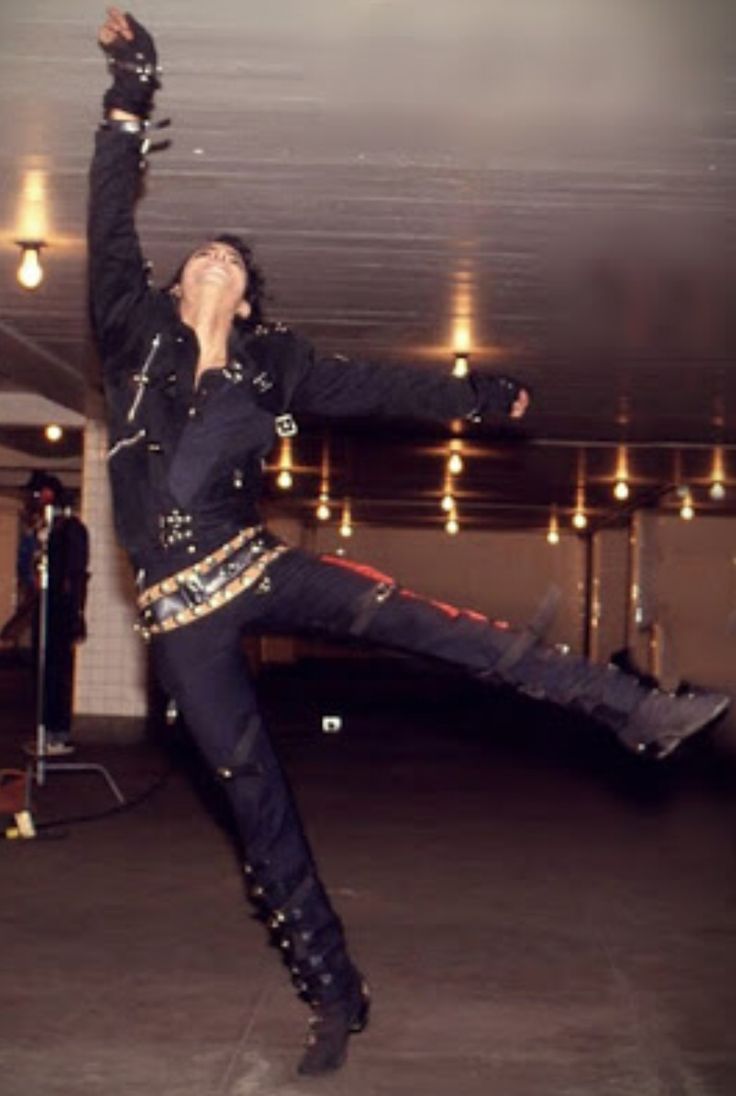 a man in black jacket doing a trick with his hands and legs up while standing on one leg