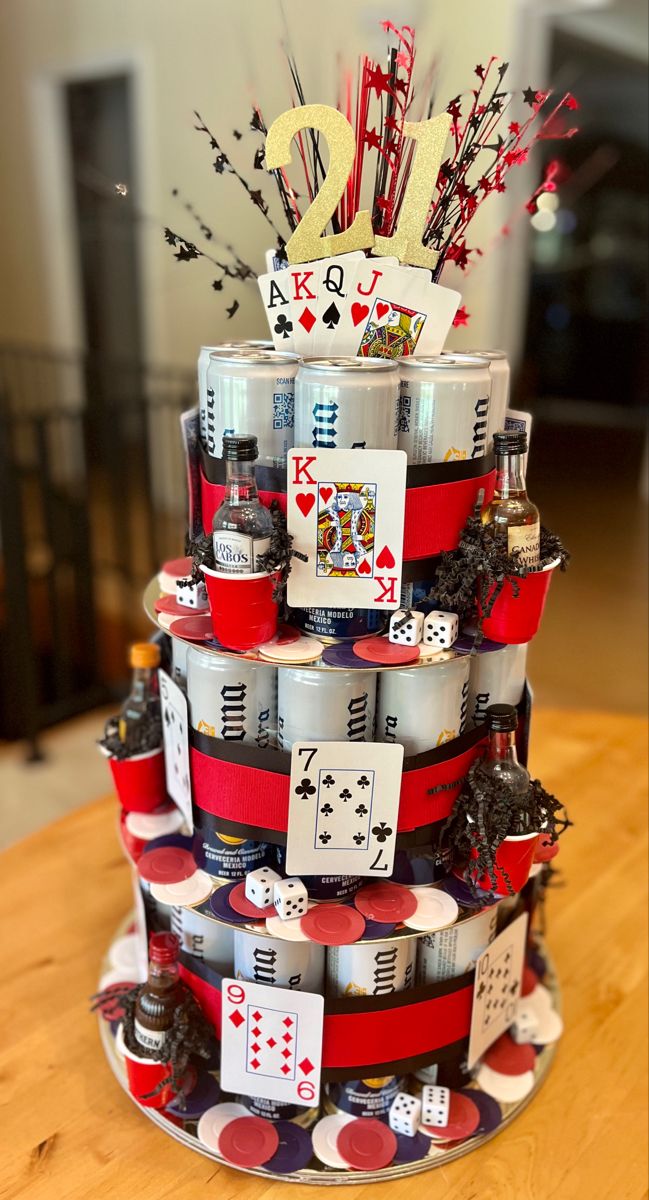 a tiered cake made out of cans and playing cards on the top, sitting on a wooden table