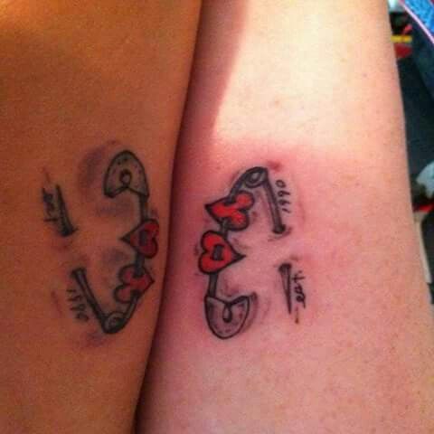 two people with matching tattoos on their arms, one has the letter e and the other has an arrow