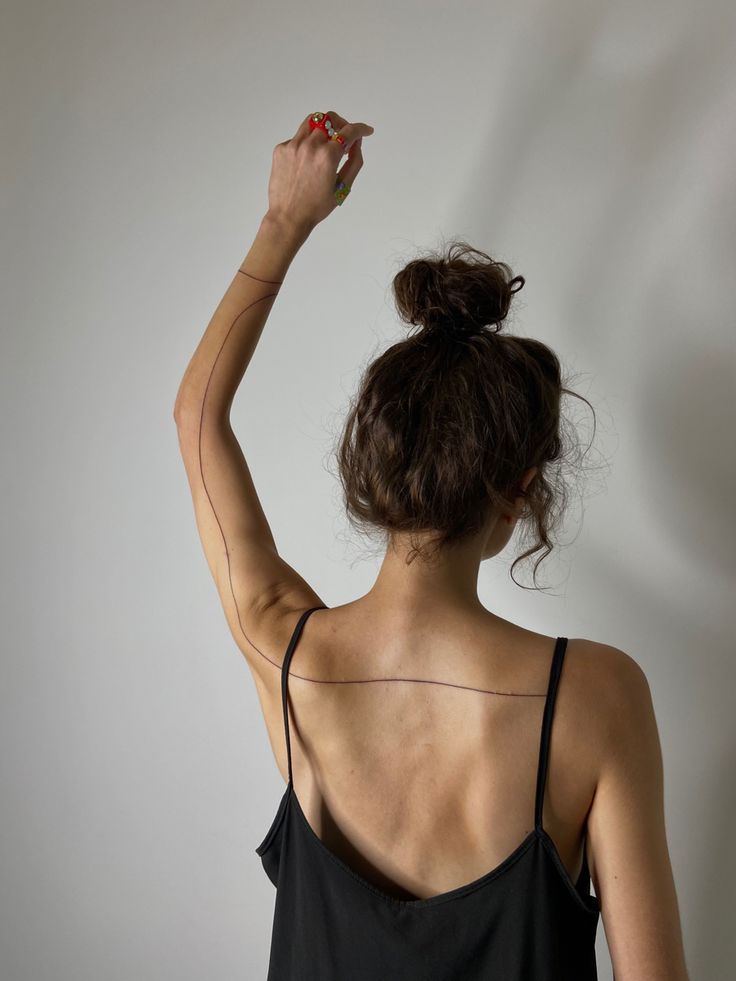 a woman in black tank top holding something up to her head