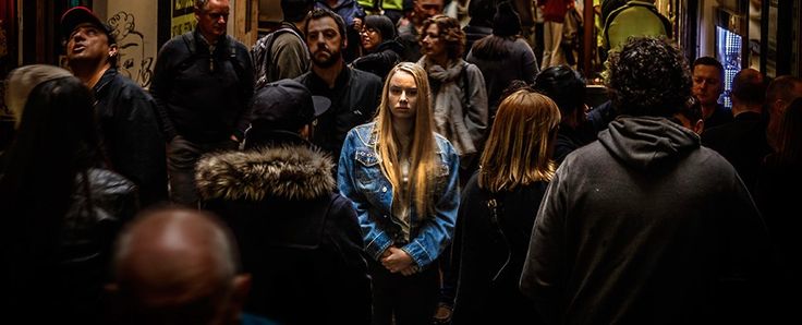 a group of people walking down a crowded hallway in a building with graffiti on the walls