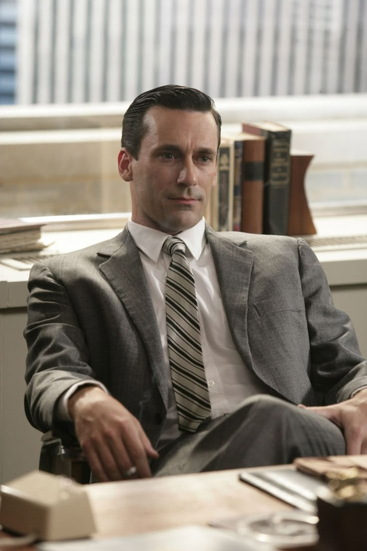 a man in a suit and tie sitting at a desk with some books on it