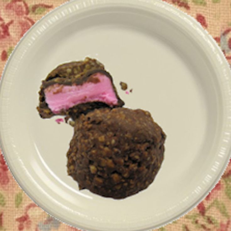 a white plate topped with two pieces of chocolate covered in pink frosting