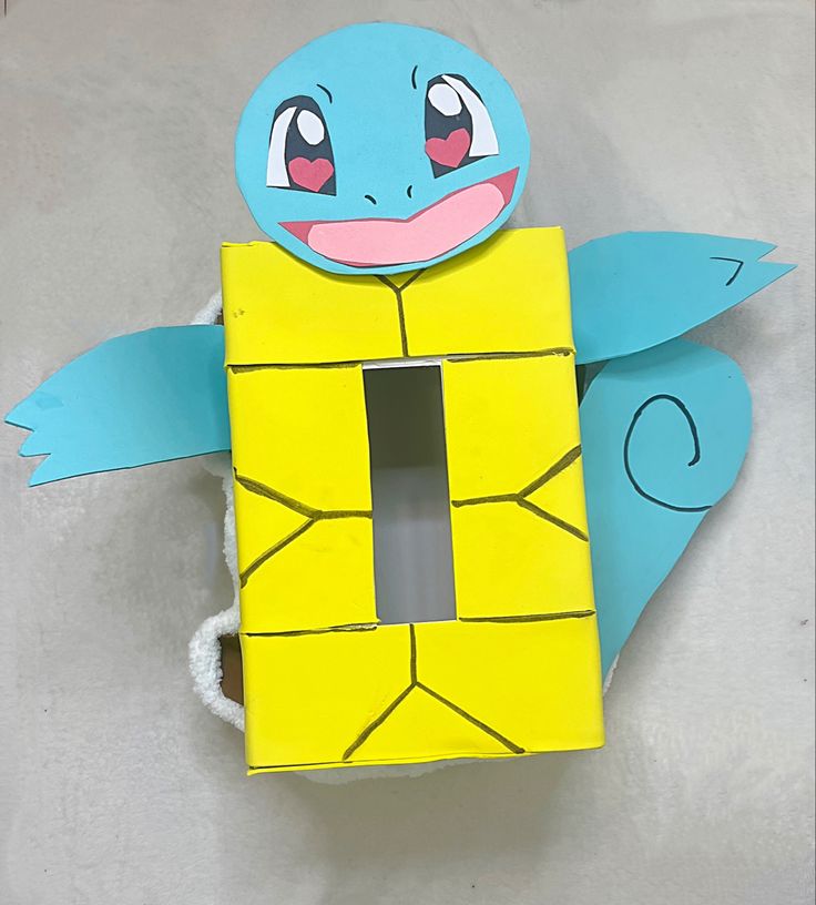 a paper cut out of a yellow box with a blue turtle on it's back