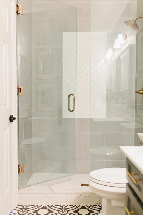 a white toilet sitting next to a shower in a bathroom under a light colored ceiling