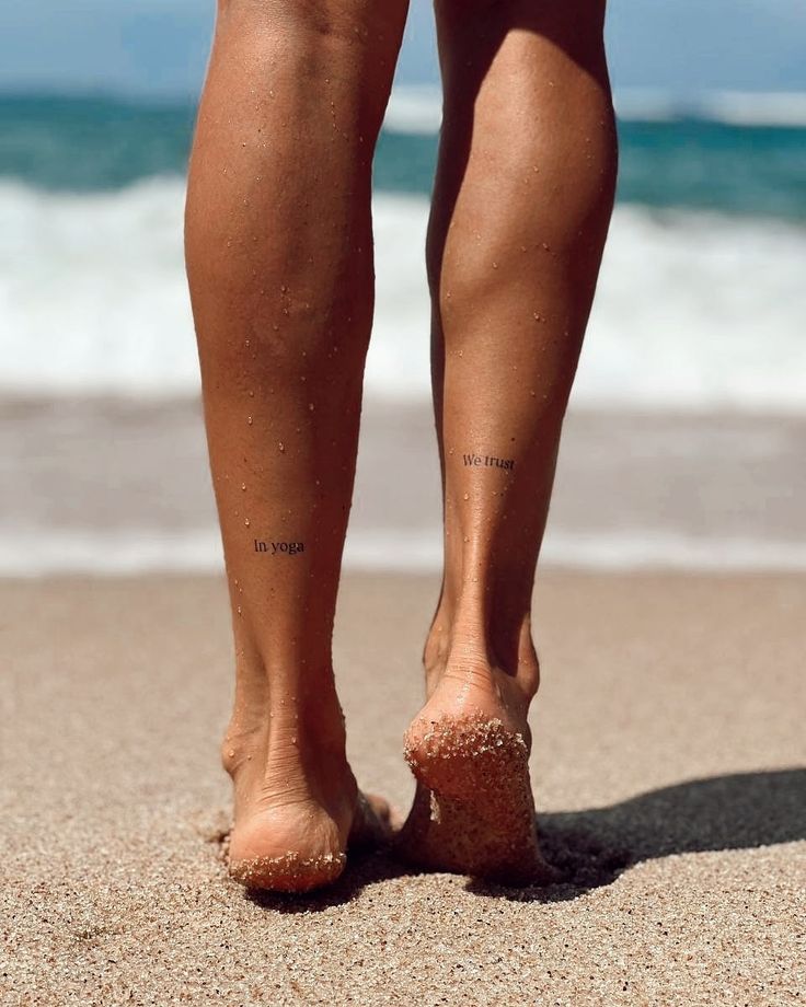 a person standing on the beach with their feet in the sand and water behind them