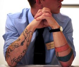 a man sitting at a table with his hands on his face and arms folded up