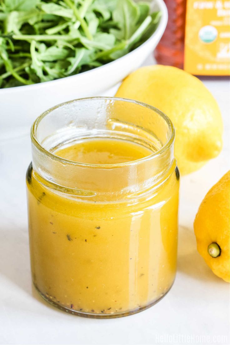 a glass jar filled with yellow liquid next to lemons