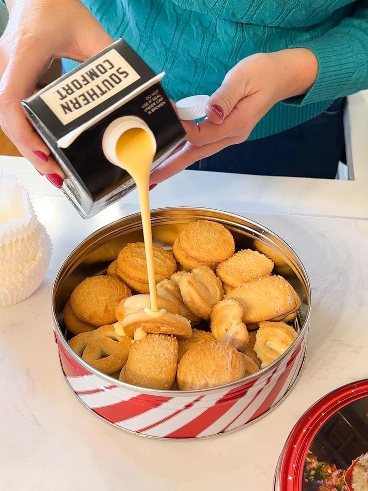 a person pouring sauce on some food in a tin pan with other dishes around it