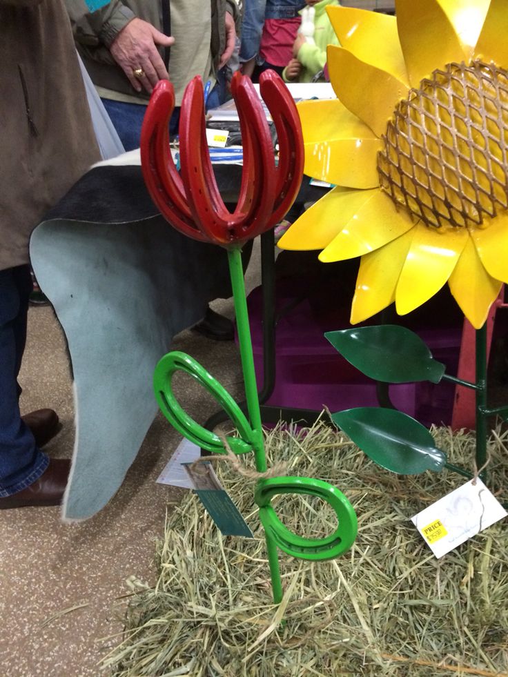 two fake sunflowers are on display in front of some hay and other items